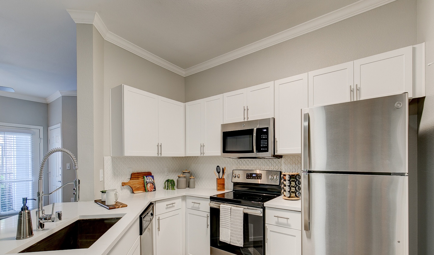 Model kitchen at our apartments in Flower Mound, featuring stainless steel appliances and wood grain floor paneling.